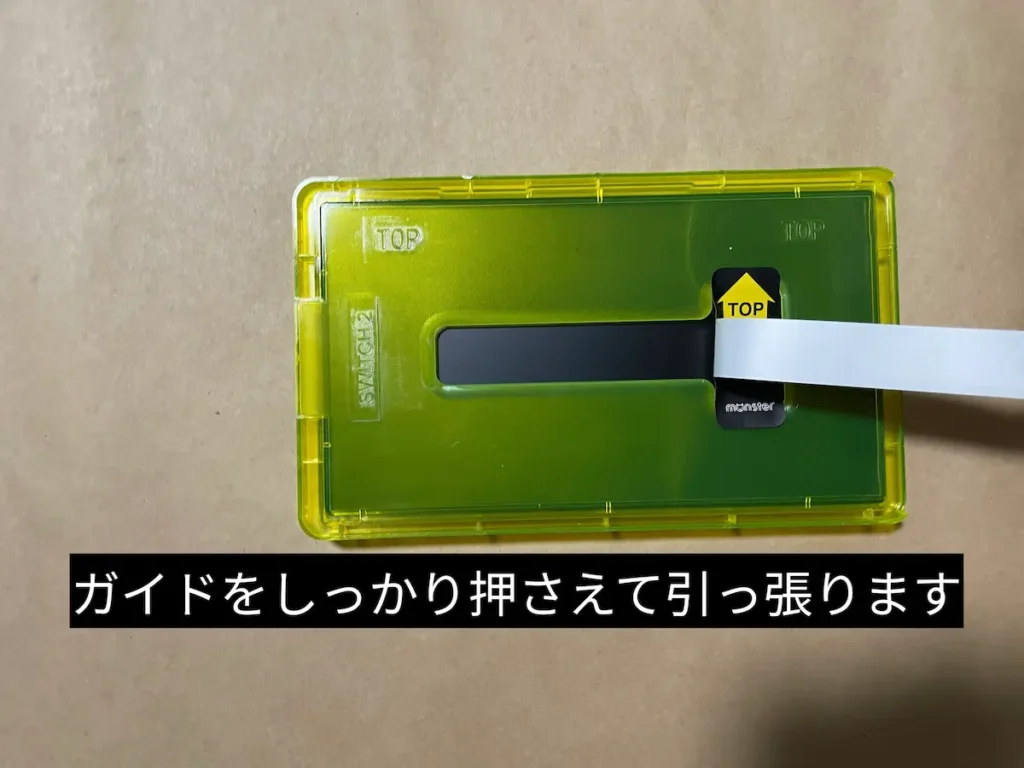 ガイドをしっかり押さえて中央のシールを引っ張るところ